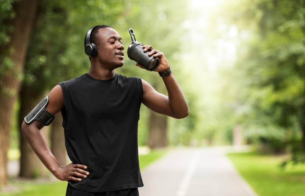 man drinking water after a park run