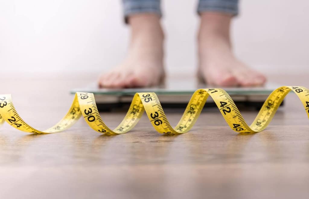 man standing on a scale with a measuring tape on the floor
