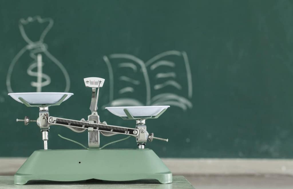 weight loss scale showing money and education on a black board