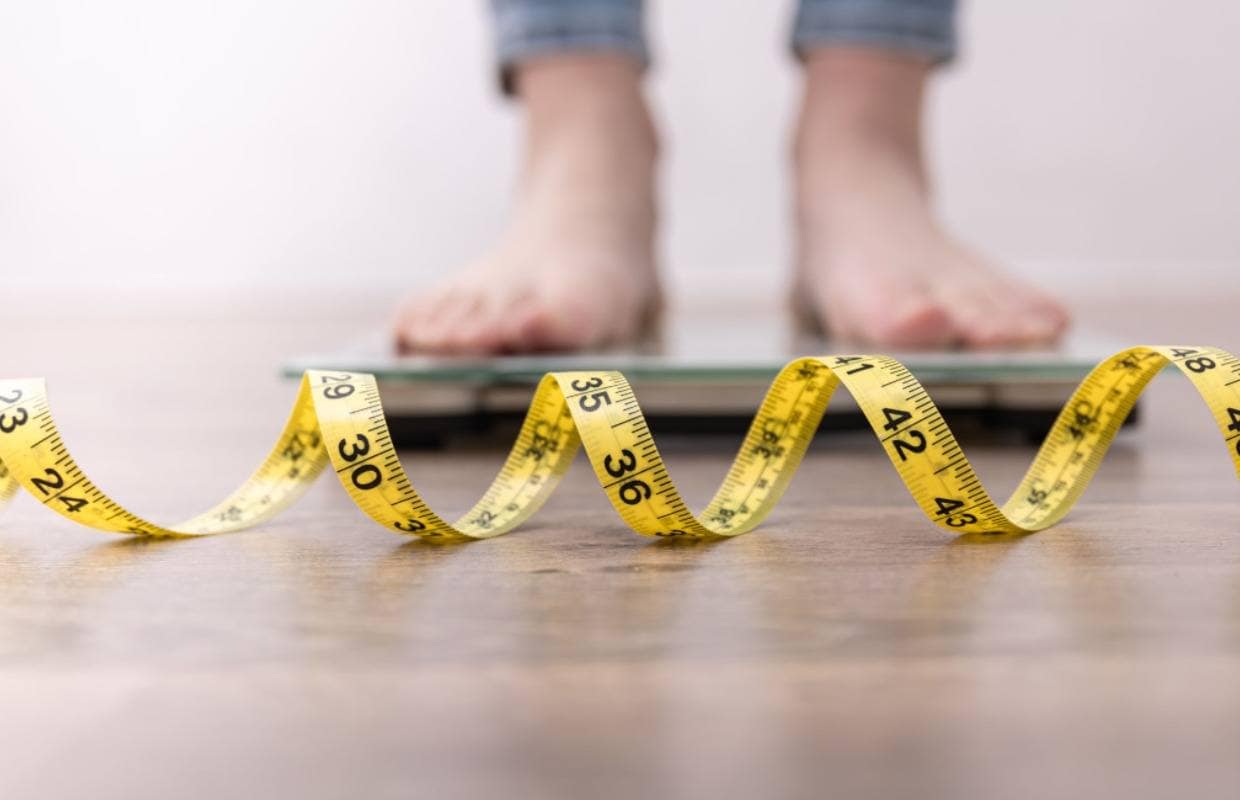 man standing on a scale with a measuring tape on the floor